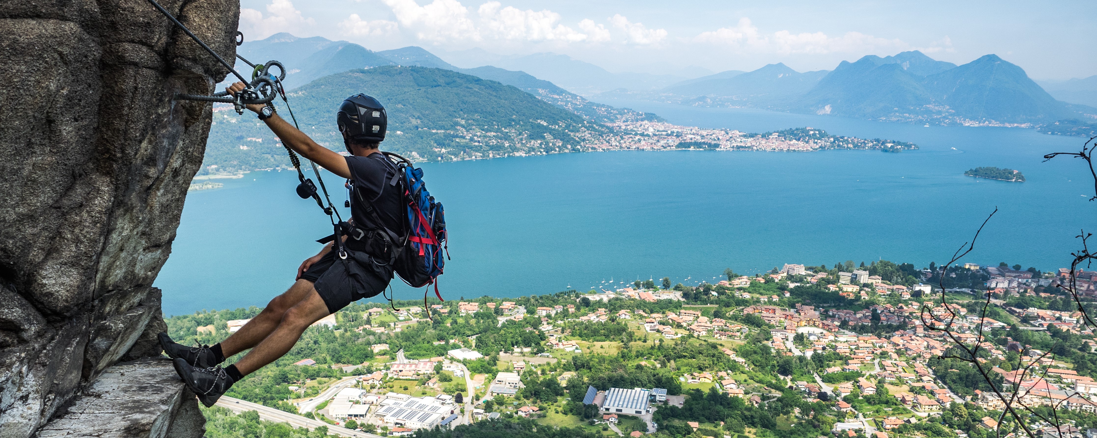 Climber on a via ferrata high above a lake in the Italian mountains
