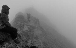 Walkers scrambling along the misty crest of Crib Goch on the Welsh 3000s
