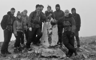 Welsh 3000s team gathered around the trig point on a misty summit