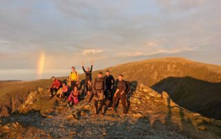 Welsh 3000s group celebrating on a summit in golden evening light