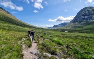 Cairngorm 4000s glen walk Cairngorm 4000s walkers on a path through a wide glen under blue skies
