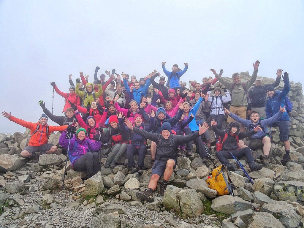Large charity group celebrating on a misty summit