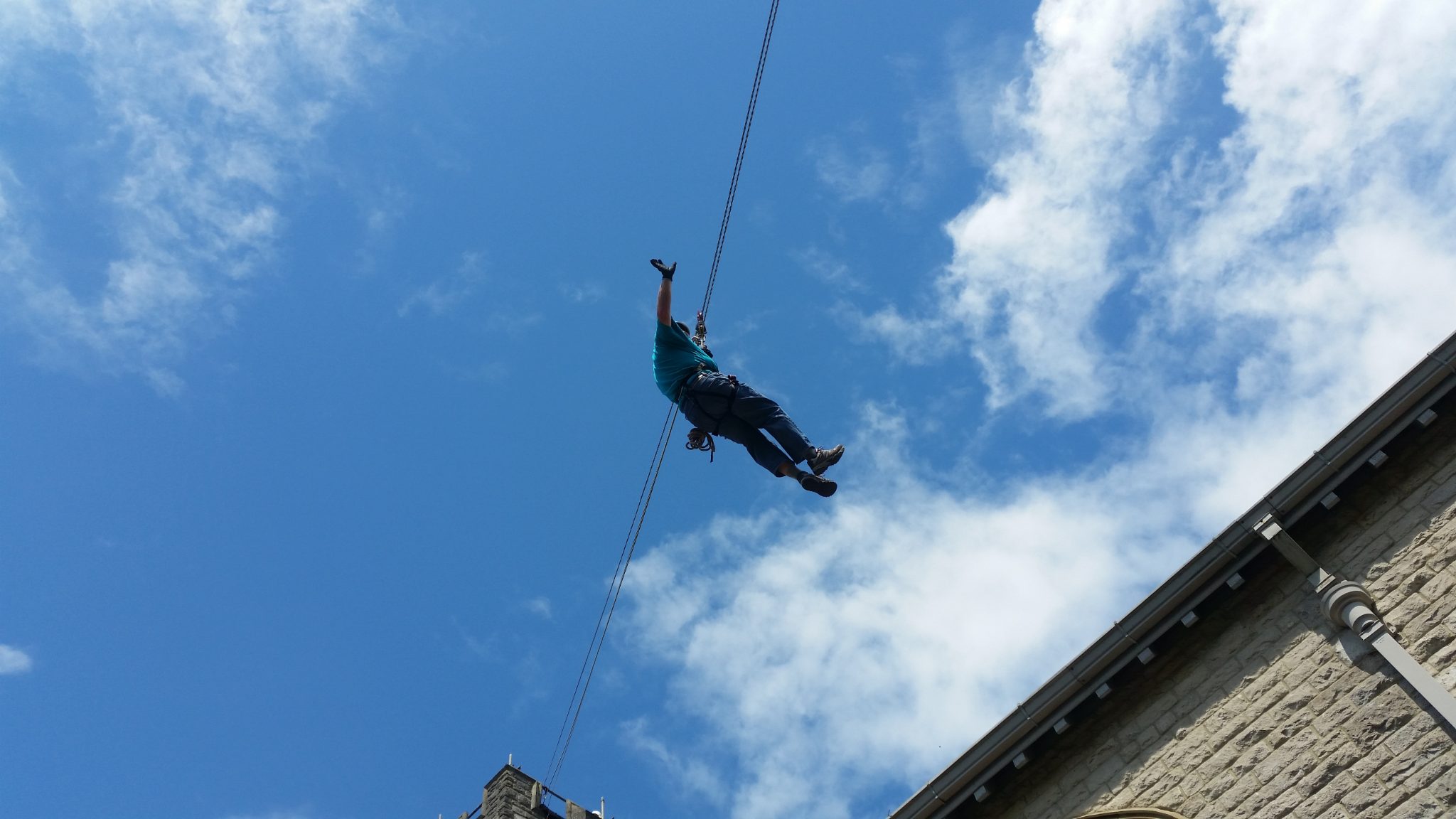 Zip wire rider silhouetted against a blue sky