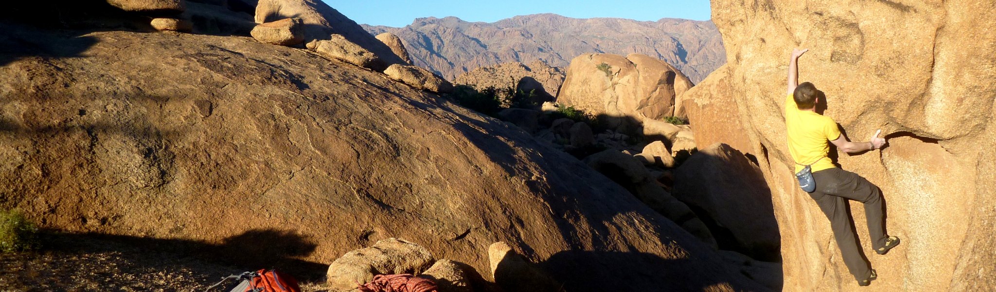 Sunlit granite slabs and boulders beneath rocky mountain peaks