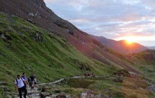 Lake District 10 Peak Challenge sunrise start Walkers setting off up a Lake District fell as the sun rises