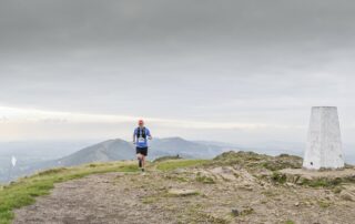Runner crossing the summit of a Malvern hill with the ridge behind