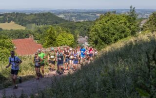 Long line of runners climbing a lane out of Malvern at the start of the trail half marathon