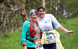 Two smiling women runners with race numbers posing at the Malvern Hills Trail Half Marathon