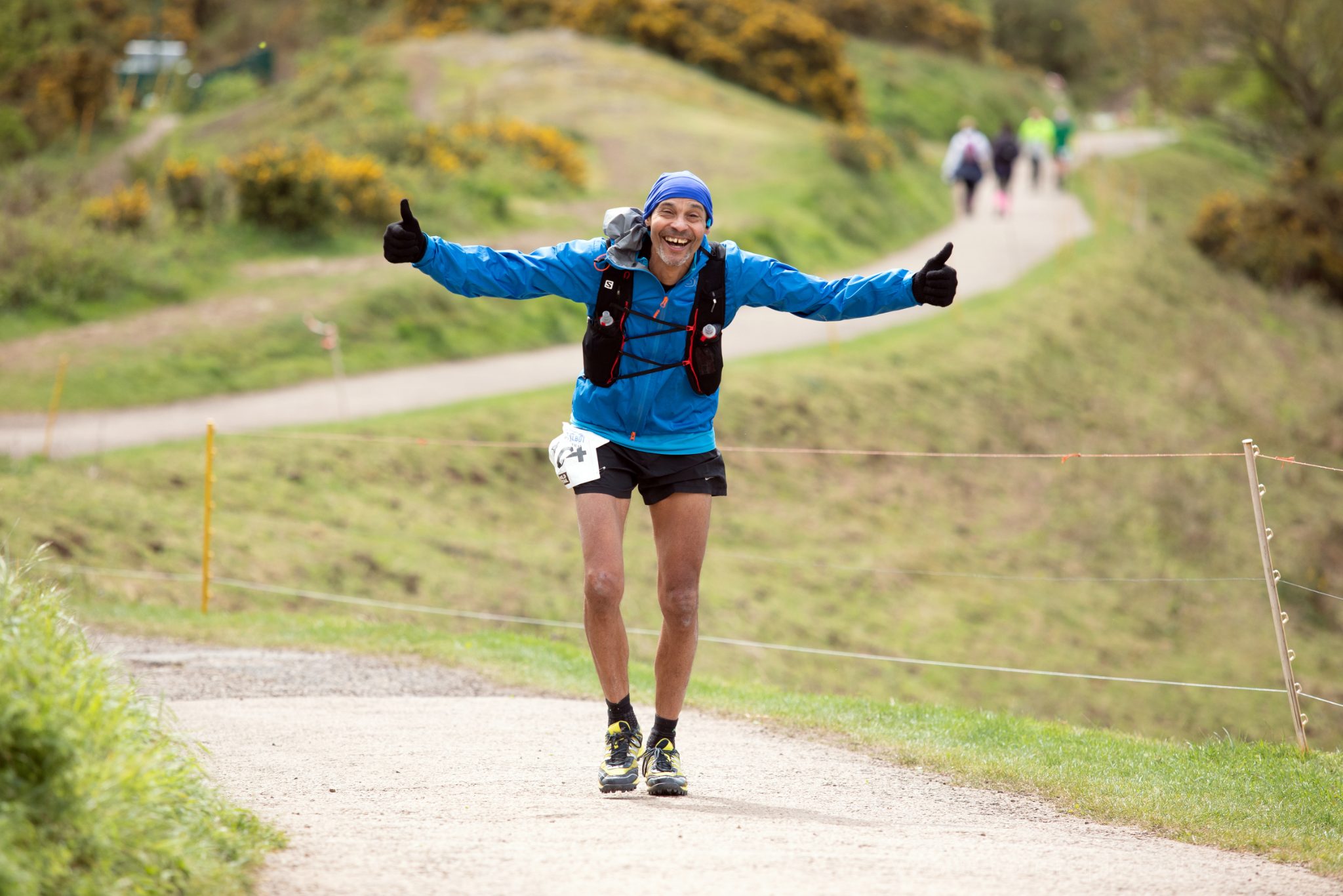 Runner with arms outstretched on a grassy trail on the Malvern Hills