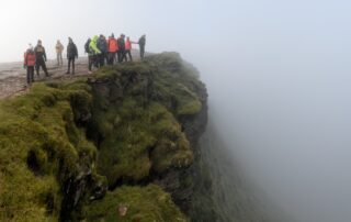 Walkers on a cliff edge in the cloud