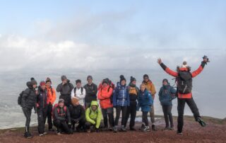 Team celebrating on a summit, one jumping for joy