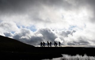 Walkers silhouetted under a stormy sky in the Brecon Beacons