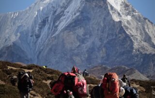 himalaya-porters-ice-face Porters on the trail beneath a huge Himalayan ice face
