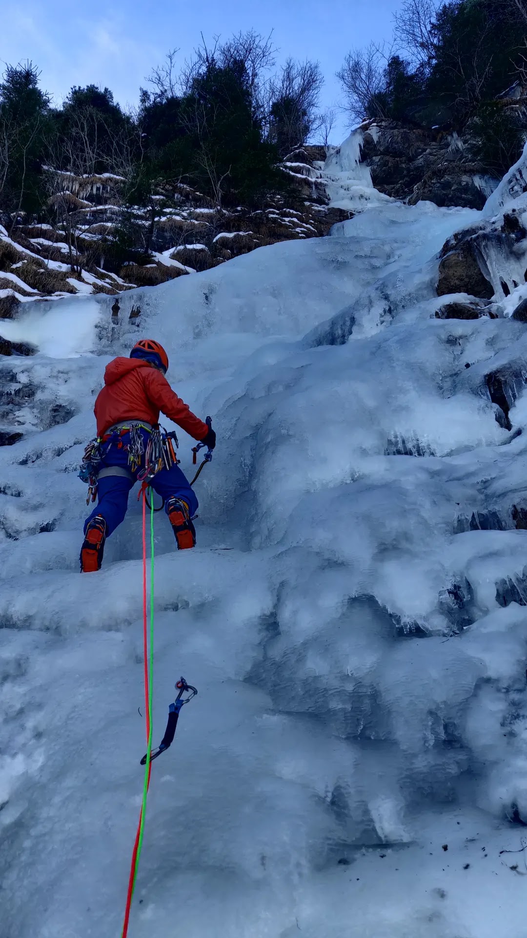 Climber leading a frozen waterfall in the Alps